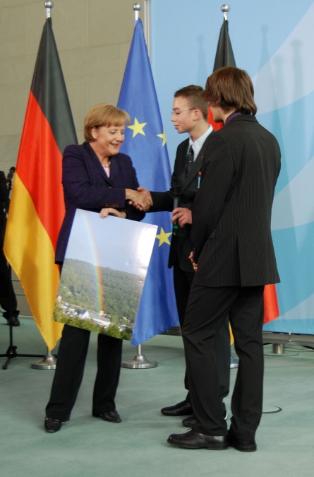 Tobias Kaufmann und Michael Schmitz schenken der Bundeskanzlerin Dr. Angela Merkel ein Bild des St. Michael-Gymnasiums