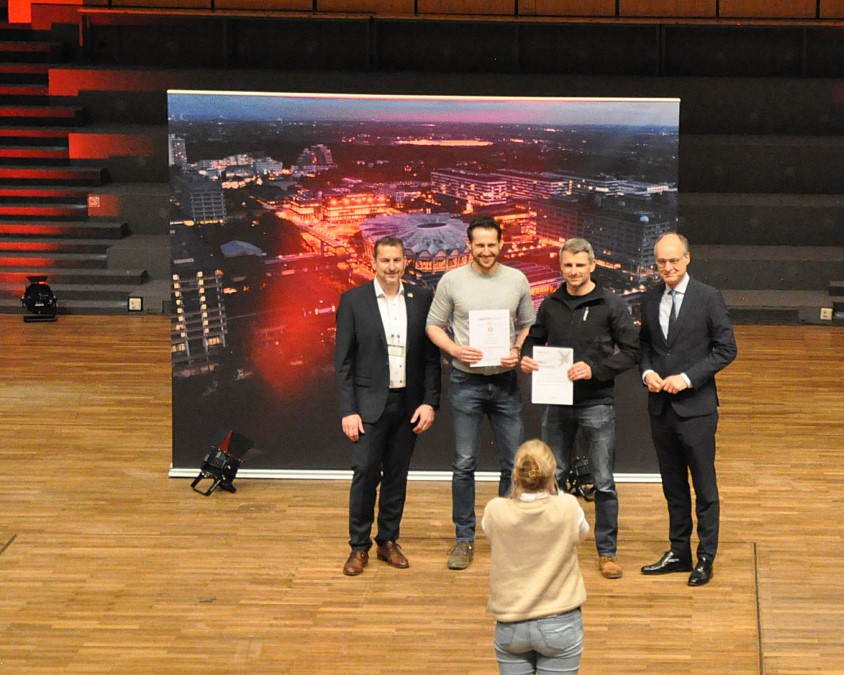 Daniel Mertens und Dennis Nebe nehmen den Preis für die beste Jugend forscht Schule von NRW entgegen